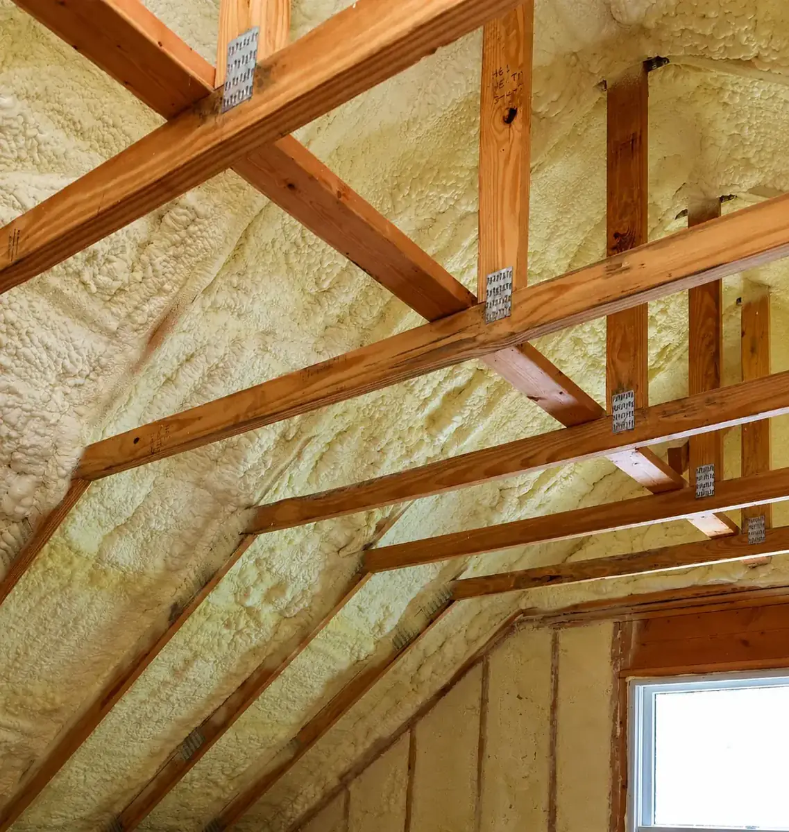 An attic roof line fully sealed with spray foam, trusses left exposed